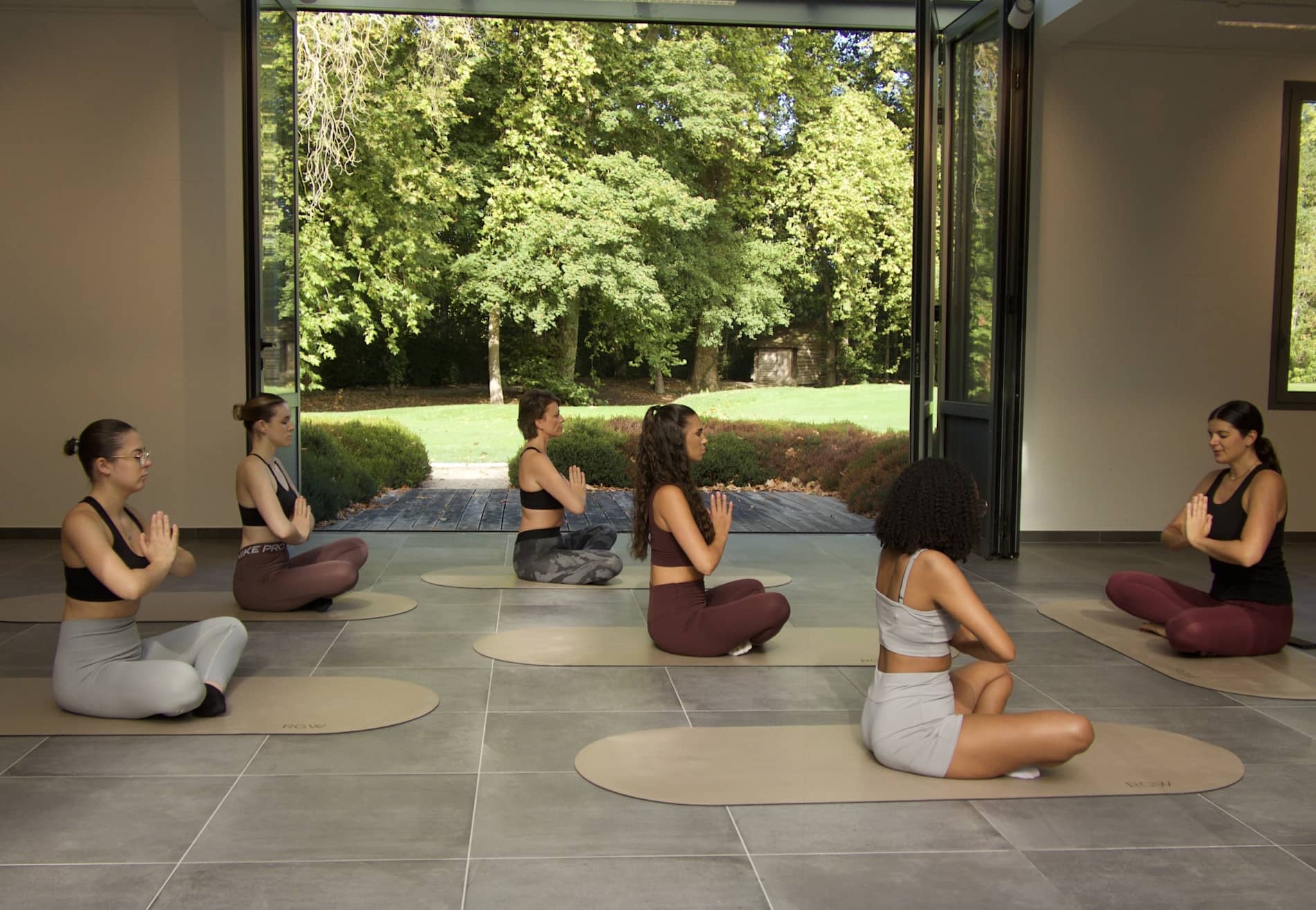 Cours de yoga en groupe dans une salle ouverte sur le parc du Château d’Augerville